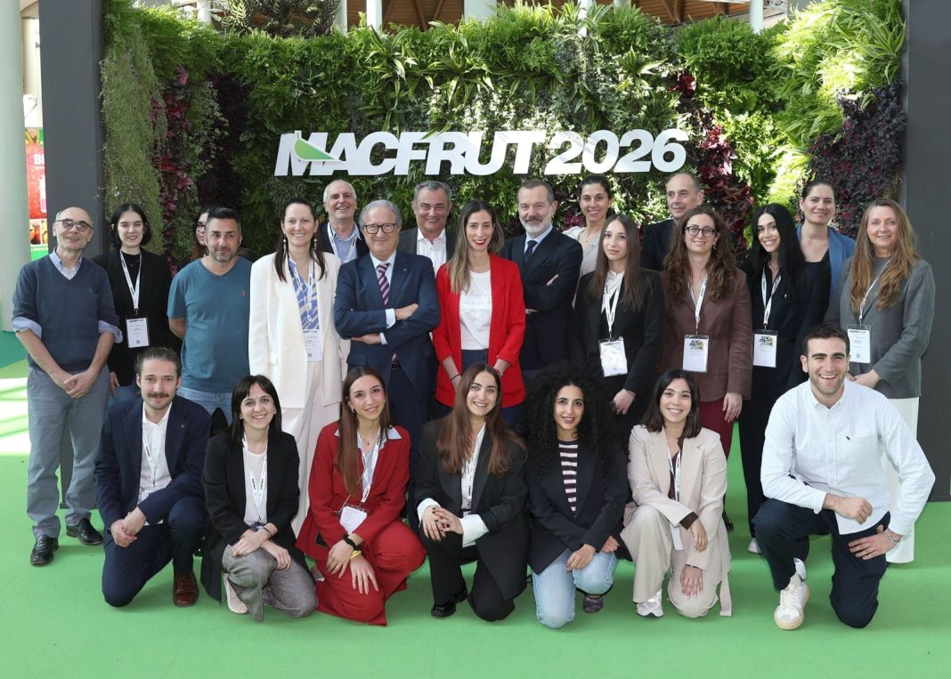 Group of professionals posing for a photo at MACFRUT 2026, standing in front of a lush green vertical garden with the event logo; everyone wears lanyards, dressed in business casual attire.