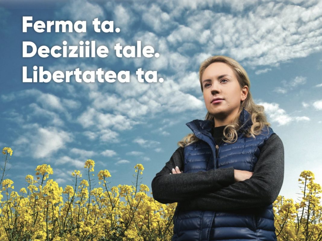 Promotional banner: a woman in a blue puffer vest stands in a yellow canola field under a blue sky, with Romanian text “Ferma ta. Deciziile tale. Libertatea ta.”